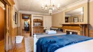 A bedroom with a large bed, a chandelier, a fireplace, and a mirror. - 1899 Historic Luxury Brooklyn Brownstone (Brooklyn)
