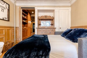 Um quarto com uma cama grande, cômoda, espelho e guarda-roupa de madeira.