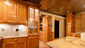 A kitchen with wooden cabinets, a granite countertop, and a brick wall. - 1899 Historic Luxury Brooklyn Brownstone (Brooklyn)