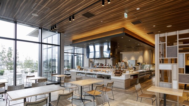 Un restaurant moderne doté d’un bar central, de grandes fenêtres et d’une variété d’aménagements pour les places assises.