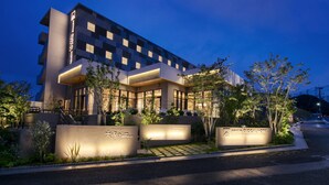 Un hôtel moderne doté d’une entrée imposante, d’une façade bien éclairée et d’un espace paysager à l’entrée.
