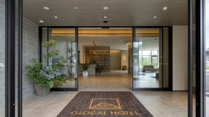 L’entrée d’un hôtel, avec un comptoir d’accueil, un espace d’attente et un aménagement intérieur moderne.
