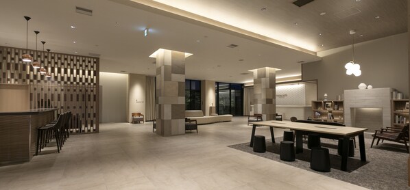 A modern hotel lobby with a reception desk, seating area, and a fireplace.