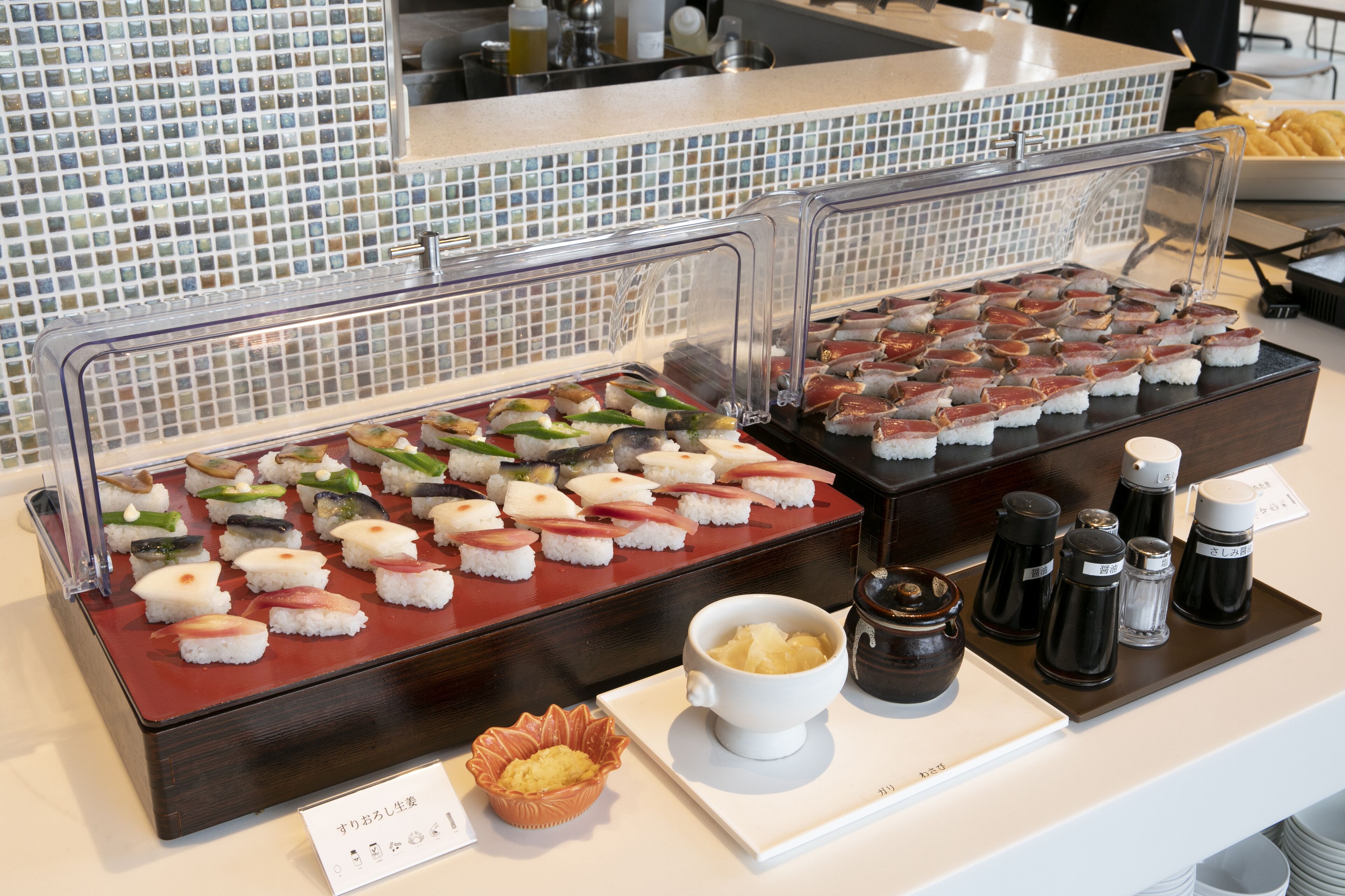 A buffet with various sushi options, a bowl of soup, condiments, and a menu sign.