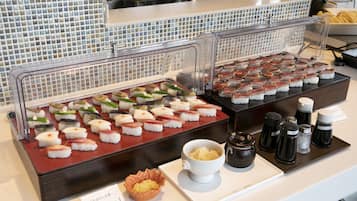 A buffet with various sushi options, a bowl of soup, condiments, and a menu sign.