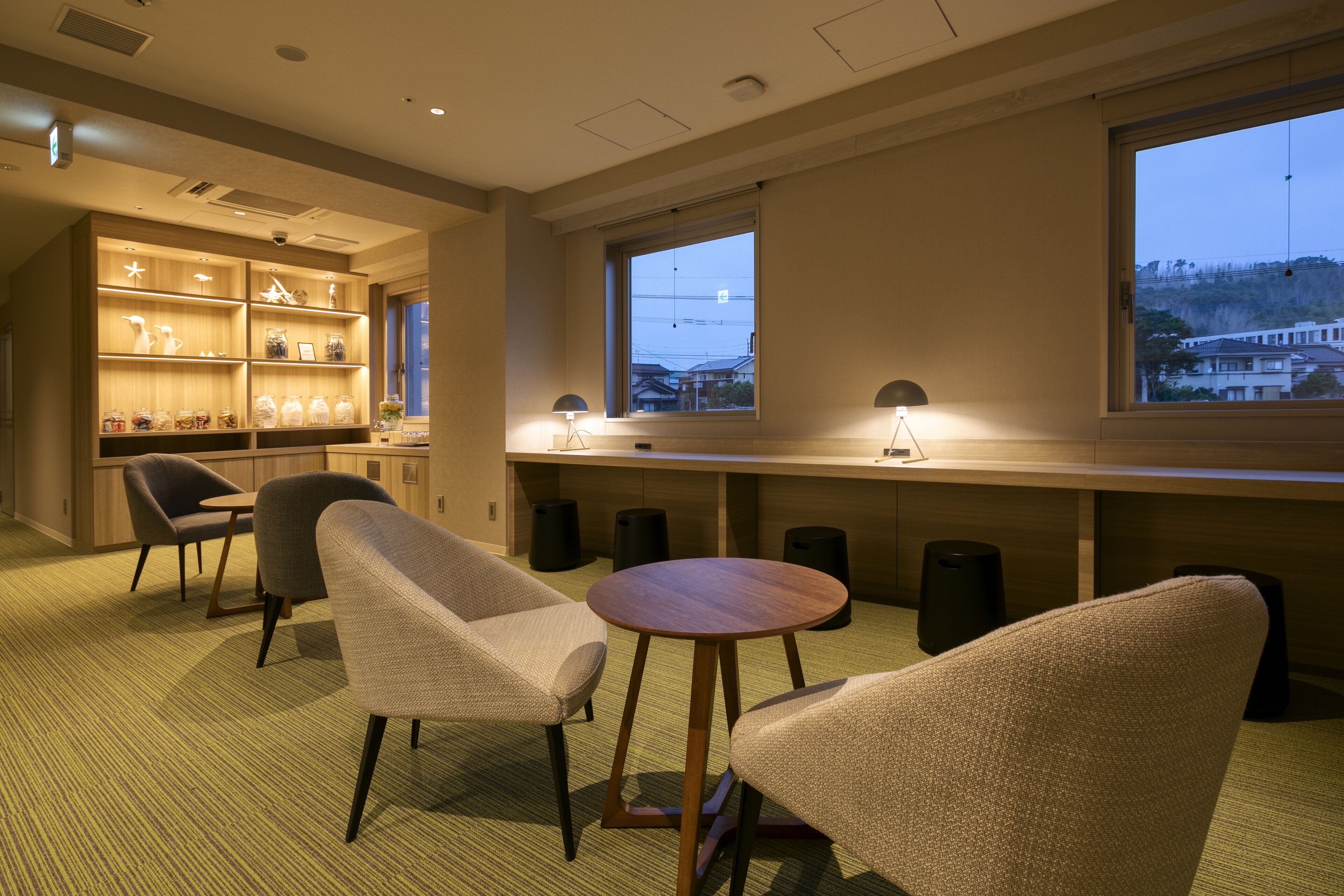 Habitación de hotel moderna con zona de estar, escritorio de madera y un amplio ventanal con vistas a la ciudad.