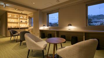 Habitación de hotel moderna con zona de estar, escritorio de madera y un amplio ventanal con vistas a la ciudad.