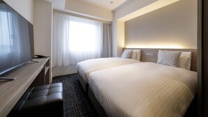Une chambre d’hôtel avec un grand lit, un bureau avec une chaise, un téléviseur à écran plat et une fenêtre avec des rideaux.