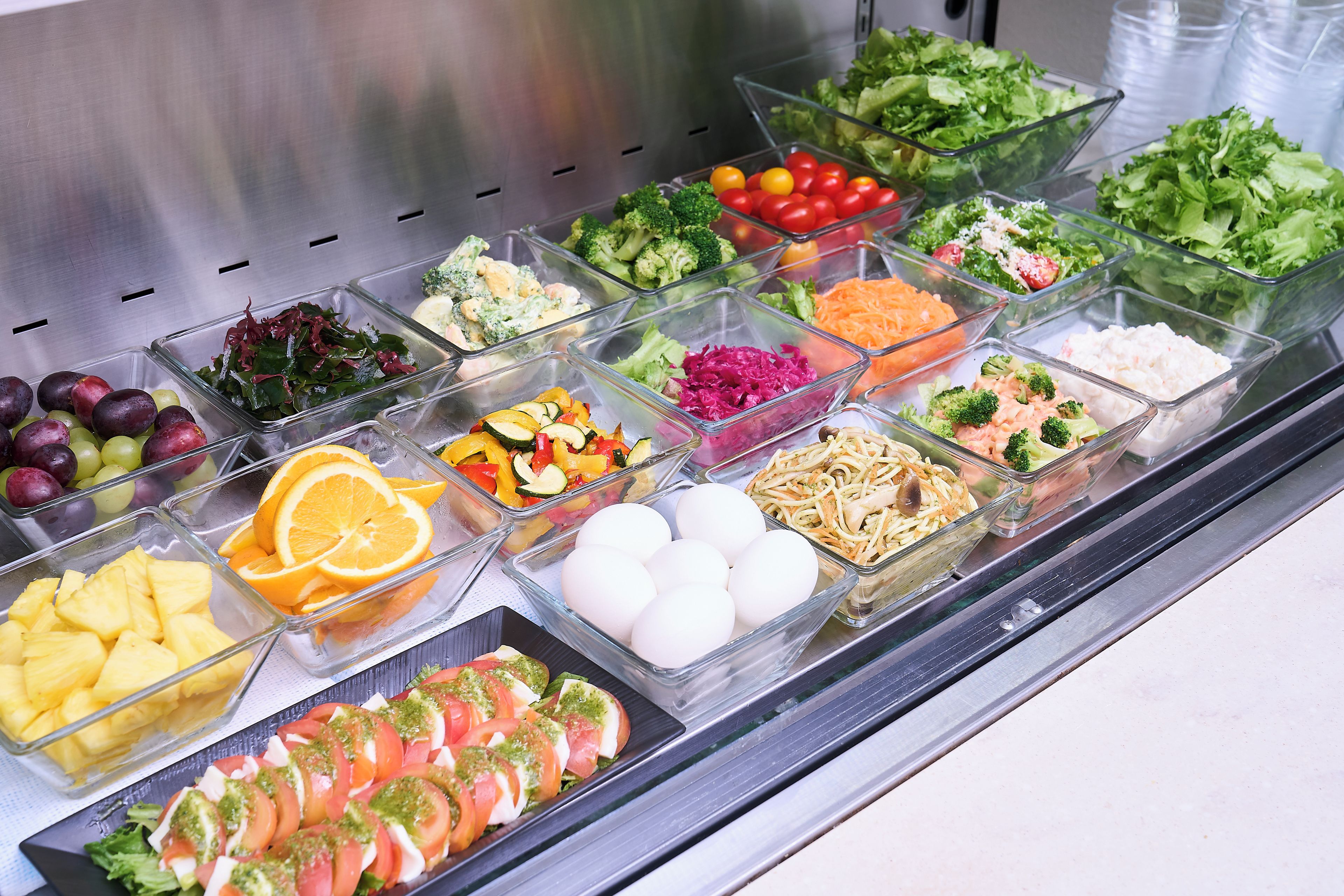 Un bufé con diferentes opciones de comida, incluyendo frutas, verduras y ensaladas.
