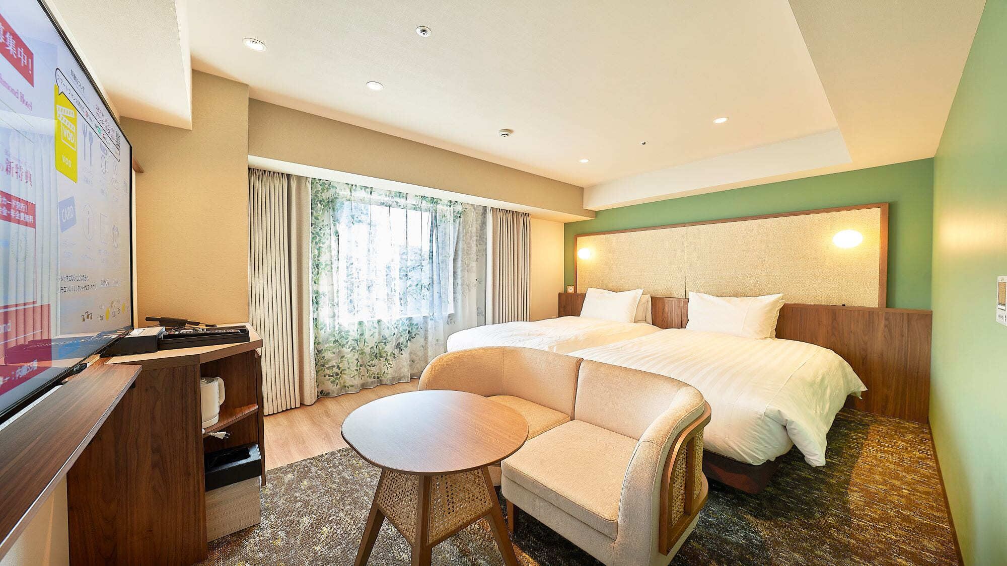 Quarto de hotel com cama, escrivaninha, cadeira e televisão.