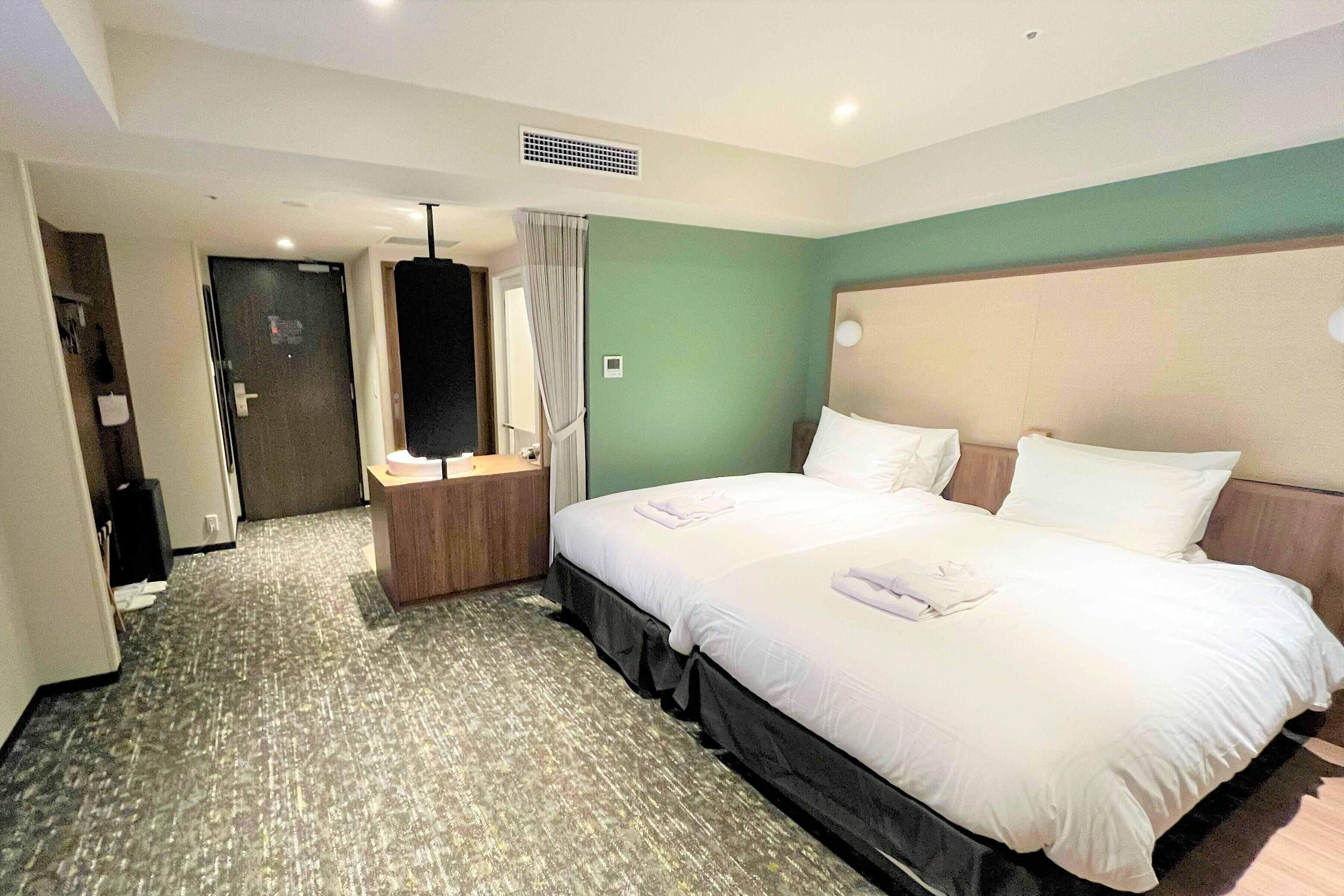 Ein Hotelzimmer mit einem großen Bett, einem Nachttisch, einem Spiegel und einer Tür zu einem Badezimmer.