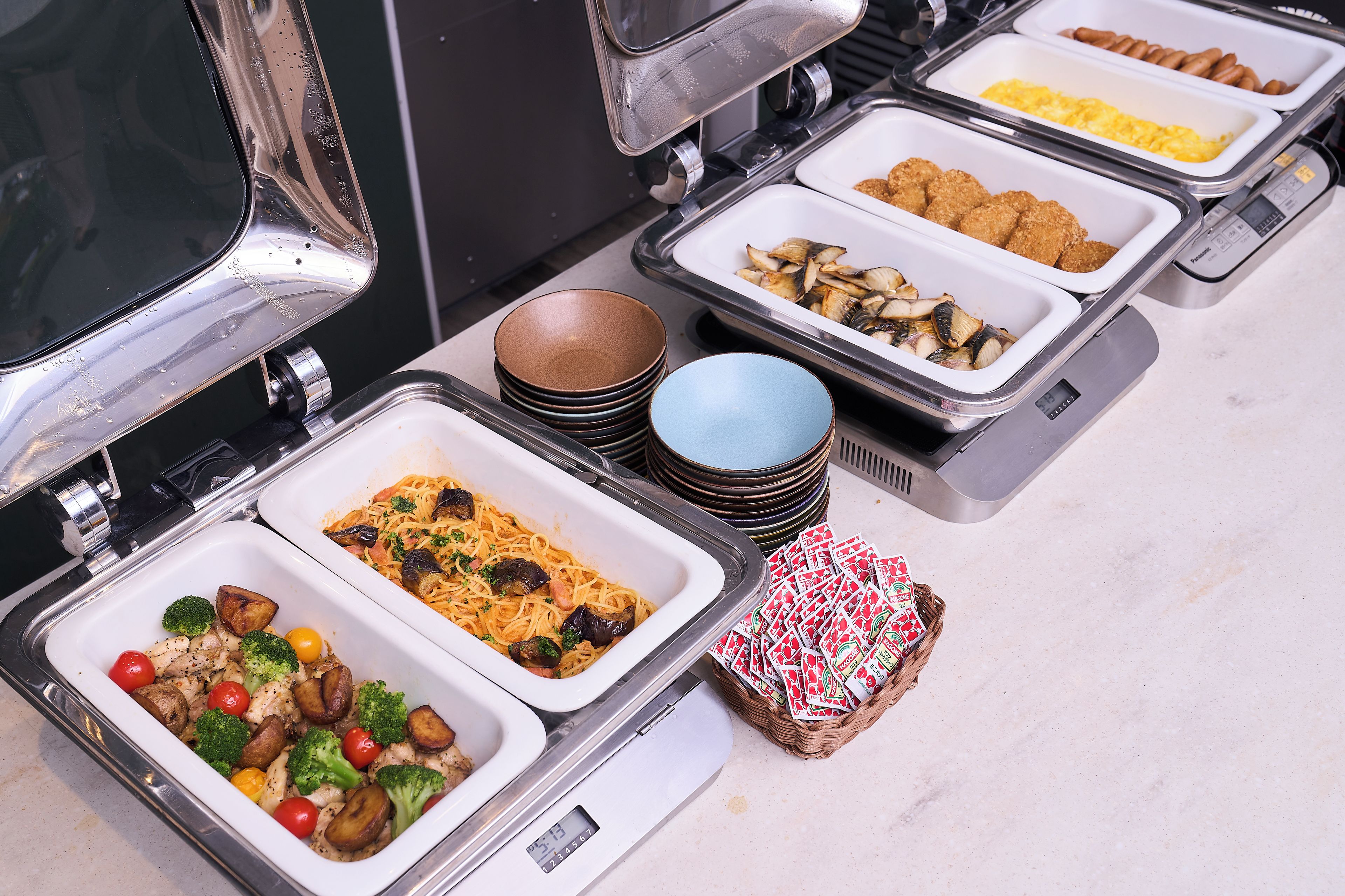Ein Buffet mit verschiedenen Speisen, darunter Pasta, Gemüse und Brot.