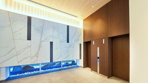 A modern lobby with marble walls, a wooden panel wall, and a built-in aquarium. - Keisei Richmond Hotel Tokyo Kinshicho (Tokyo)