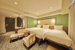 Two large beds with white linens, a small table and chair, and a wicker armchair.