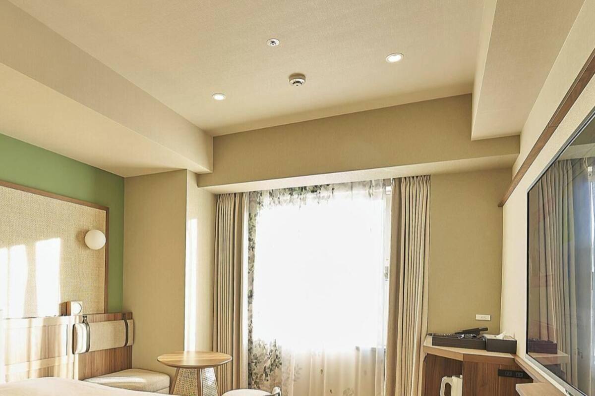 Een superior kamer met een queensize bed, een kleine tafel, een televisie en een raam met gordijnen.