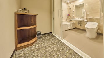 Un baño moderno con ducha, lavamanos e inodoro. Se observa una estantería de madera con artículos de aseo personal y un cesto de basura.
