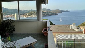 Un balcone con vista sul mare, un tavolo e piante in vaso.