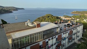 Un edificio con terrazza sul tetto che si affaccia su una zona costiera con barche e vista libera sul mare.