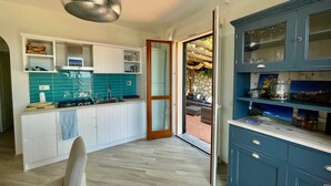 Une cuisine moderne avec des meubles blancs, un plan de travail bleu et un luminaire suspendu.