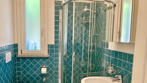 Une salle de bain comprenant des toilettes, une douche avec une porte en verre et un lavabo.