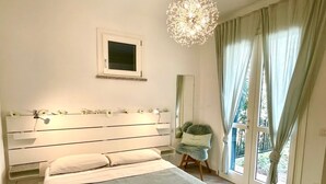 Une chambre à coucher comprenant un lit, une table de chevet, une chaise, une fenêtre avec des rideaux et un lustre.