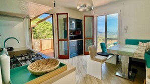 Une cuisine moderne équipée d’une cuisinière à gaz, d’une grande fenêtre et d’un coin repas avec une table et des chaises.