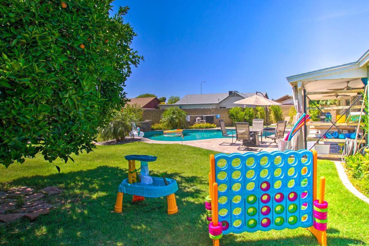 A backyard with a swimming pool, a play area with a hopscotch board, and a covered patio.