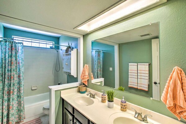 A bathroom with a double sink, a shower, and a large mirror.