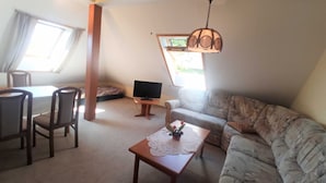 A cozy living room with a sofa, a coffee table, a TV, and a dining area with chairs and a table. - Whg. 3 - Holiday apartment in Seebad Bansin on the island of Usedom Baltic Sea (Heringsdorf)