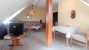 A cozy living room with a sofa, a coffee table, a TV, and a dining area with a table and chairs. - Whg. 3 - Holiday apartment in Seebad Bansin on the island of Usedom Baltic Sea (Heringsdorf)