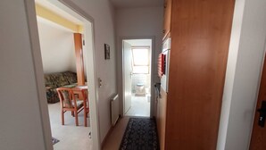 Een gang die leidt naar een woonkamer met een bank en een eettafel.
