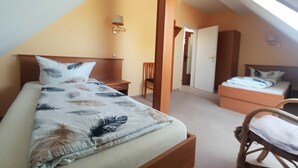 Een slaapkamer met een bed, een stoel, een nachtkastje en een deur naar een andere kamer.