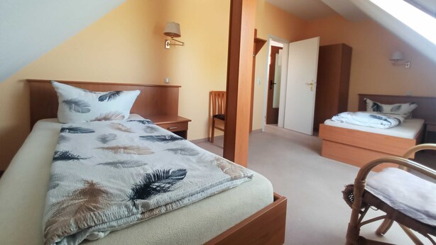 A bedroom with a bed, a chair, a nightstand, and a door leading to another room. - Whg. 5 - Ferienwohnung in Seebad Bansin auf Insel Usedom (Heringsdorf)