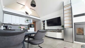 Una cocina moderna con armarios blancos, un televisor de pantalla plana y un horno empotrado.