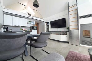 A modern kitchen with white cabinets, a flat-screen TV, and a built-in oven. - Haus Besch - Apartment Fernweh - Fernweh: 86m², 3-room, 4 pers., balcony, WLAN, (Mönchgut)