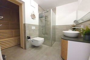 A modern bathroom with a toilet, shower, and sink. - Haus Besch - Apartment Fernweh - Fernweh: 86m², 3-room, 4 pers., balcony, WLAN, (Mönchgut)
