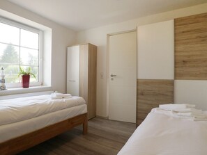 Una camera da letto con un letto, un armadio, una porta e una finestra con una pianta.
