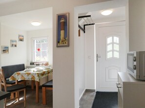 A dining area with a table set for four, a black sofa, and a window with a view. - Troja Ferienwohnung, Deutschland (Kalkhorst)