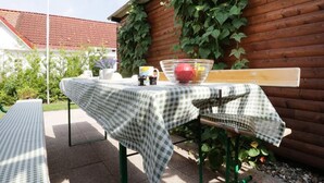 An outdoor table with a checkered tablecloth, a bowl of fruit, and a cup. - Troja Ferienwohnung, Deutschland (Kalkhorst)