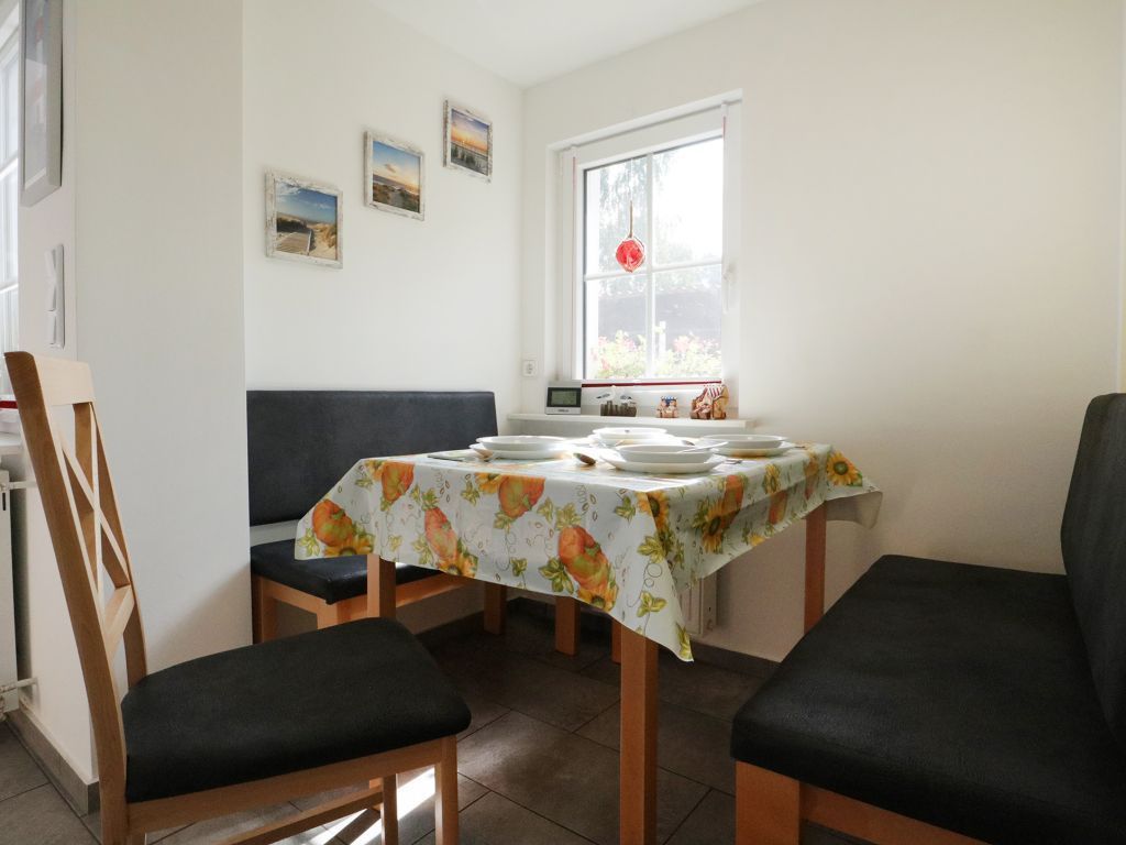 A dining area with a table set for four, a window with a view, and a chair with a cushion.