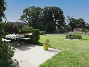 Eine Terrasse mit Tisch und Stühlen, einem Grill und einem kleinen Gartenbereich mit einem Blumentopf.