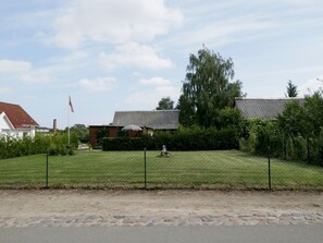 Uma área residencial com gramado, cerca e casas com telhados vermelhos.