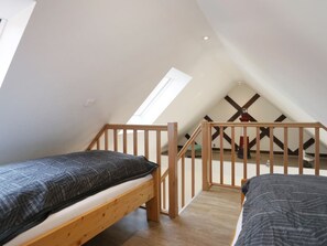 A small, cozy attic bedroom with two wooden bunk beds, a sloped ceiling, and a skylight. - Troja Ferienwohnung, Deutschland (Kalkhorst)