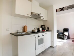 Uma cozinha moderna com armários brancos, forno embutido e máquina de café.