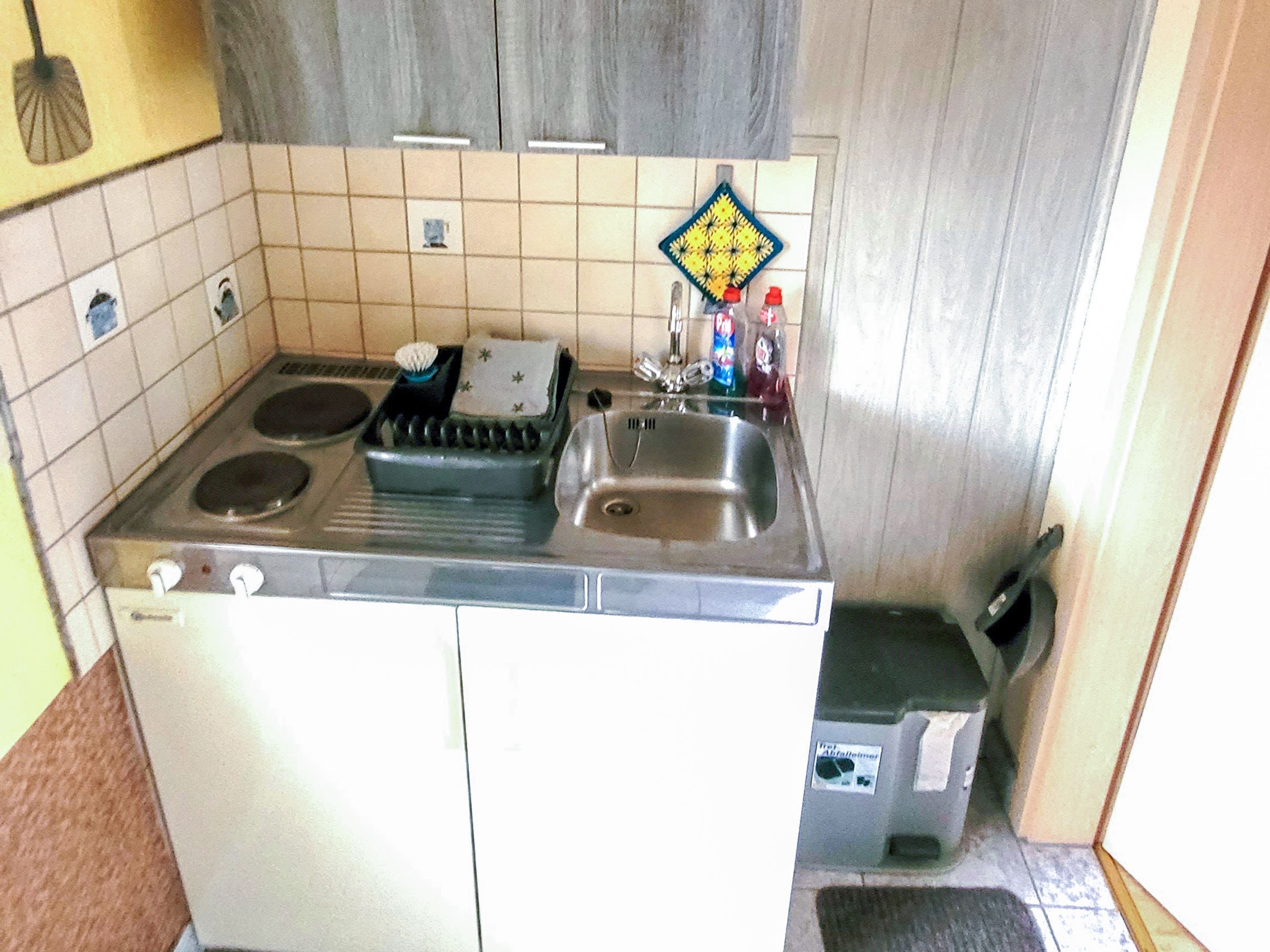Une cuisine de taille réduite, équipée d’une cuisinière, d’un évier et d’un petit plan de travail.