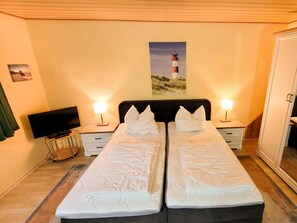 A double room with two beds, a TV, bedside lamps, and a painting of a lighthouse.