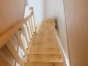 A wooden staircase with a handrail, leading upwards.