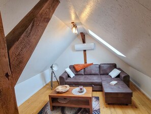 Une chambre à coucher confortable, aménagée en style « loft », avec un canapé sectionnel en cuir marron, une table basse en bois et un lampadaire.