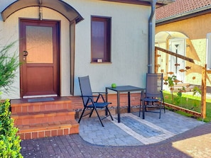 Een terras met een tafel en stoelen, een houten deur en een raam.