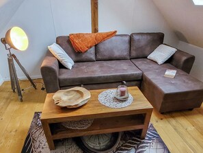A cozy living room with a brown leather sofa, a wooden coffee table, and a floor lamp.